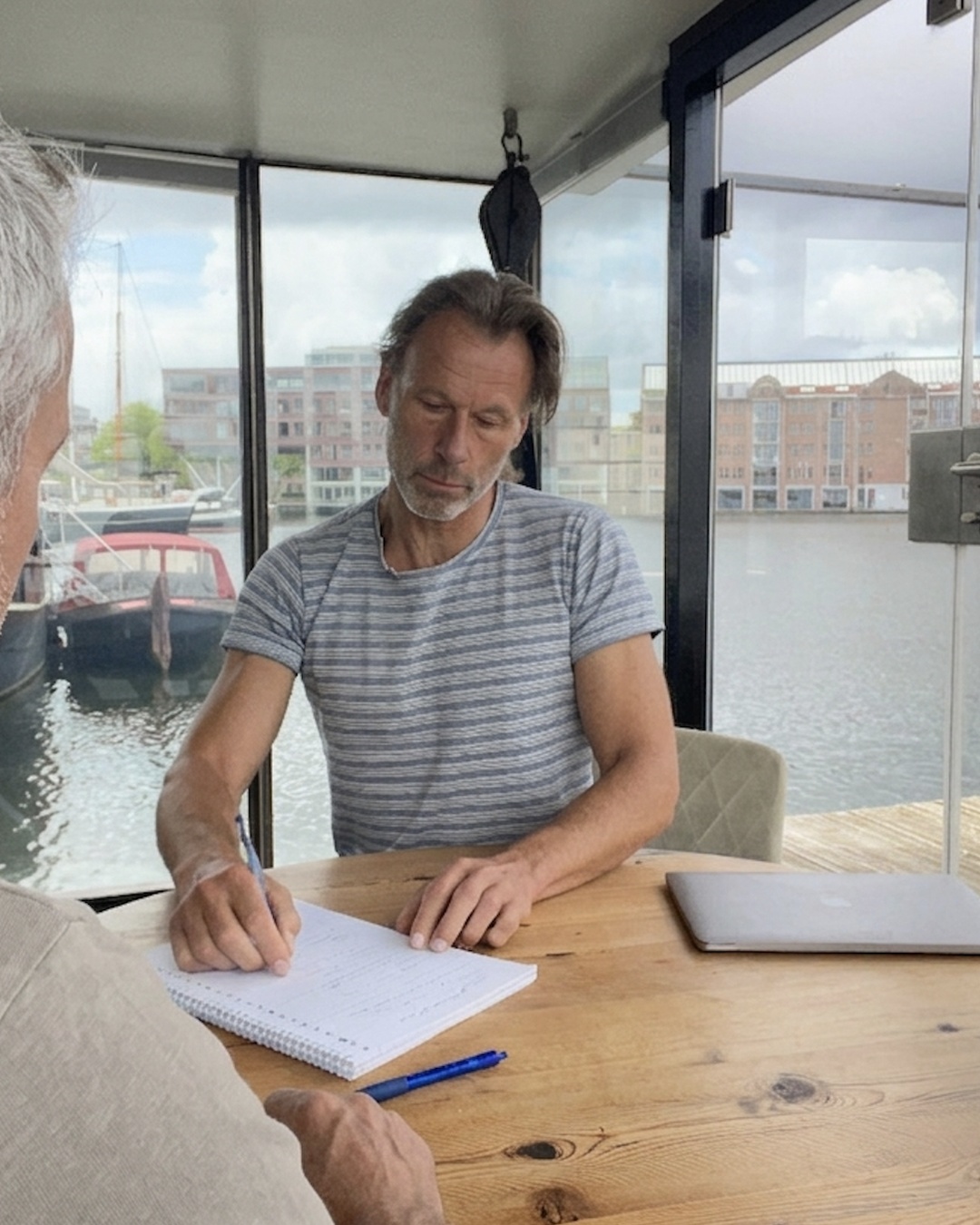 Edwin Baints maakt aantekeningen tijdens een gesprek in zijn praktijk aan het water in Amsterdam